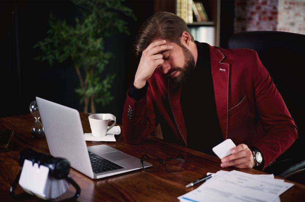 A person holding their head in discomfort, illustrating the connection between emotional stress and physical pain.