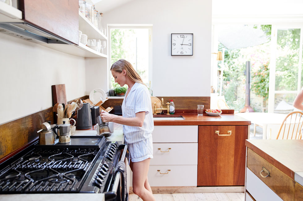 Woman wearing pajamas sitting comfortably in a cozy living room, surrounded by home decor.